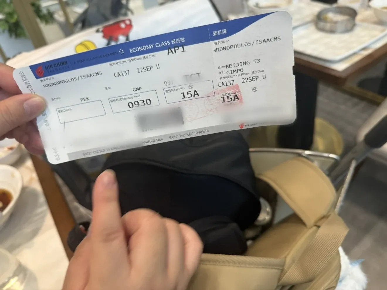 Isaac holding his Air China boarding pass for flight CA137 from Beijing to Gimpo on 22 September, with the barcode and ticket numbers blurred.