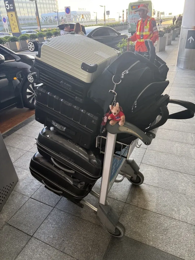 An airport trolley stacked with suitcases and bags.