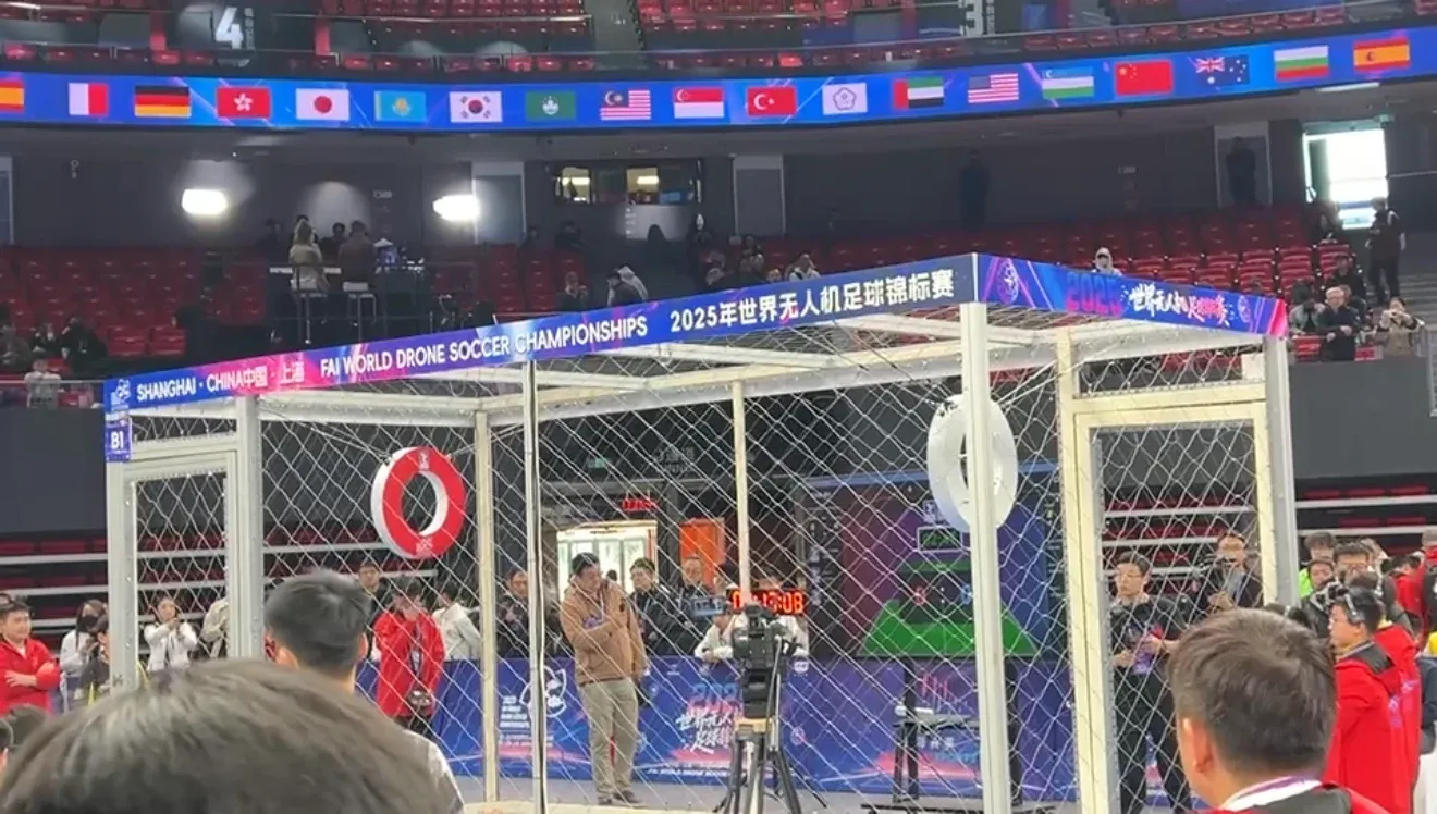 The drone soccer arena at the FAI World Drone Soccer Championships in Shanghai, a netted cage under a banner of competing nations' flags including Australia's.