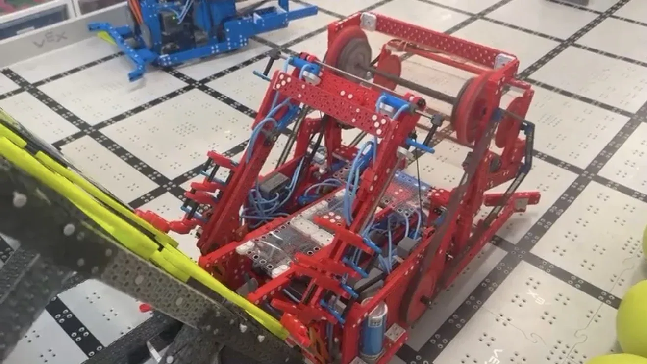 A red VEX IQ robot on the Rapid Relay field.