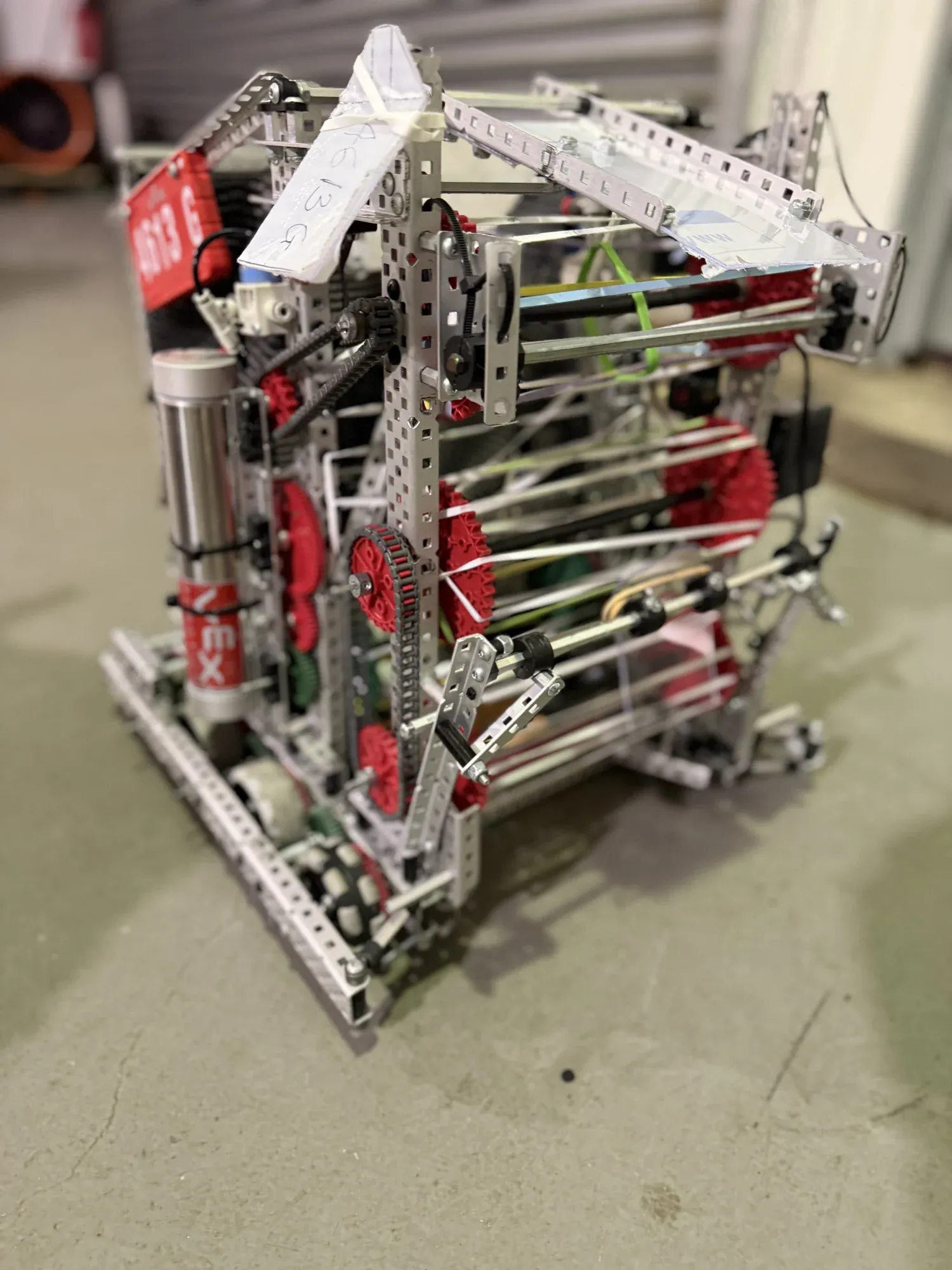 A VEX V5 robot with red flex wheels and a metal frame, with the 4613 team plate on the side.
